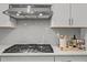Stainless steel range hood above a cooktop and herringbone tile backsplash complements the white counters and cabinets at 1026 Janiskee Rd, Durham, NC 27703