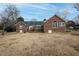 Red brick home's backyard featuring a wooden deck and lawn with trees at 104 E Laramie Dr, Mebane, NC 27302