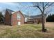 Red brick home's backyard featuring a wooden deck and lawn with mature trees at 104 E Laramie Dr, Mebane, NC 27302