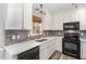 Modern kitchen featuring white cabinets, dark appliances, stone backsplash, and under cabinet lighting at 112 Solstice Cir, Cary, NC 27513