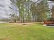 A wide green lawn, a raised red deck, and many tall trees are featured in this backyard at 1201 Clematis St, Knightdale, NC 27545