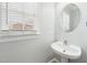 Bright half-bath with a pedestal sink, round mirror, and large window at 1201 Clematis St, Knightdale, NC 27545