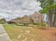A spacious brick home with mature trees, a well-manicured lawn, and classic black shutters on a cloudy day at 1201 Clematis St, Knightdale, NC 27545