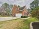 A brick home showcasing a two-car garage, a long driveway, and tidy landscaping against a cloudy sky at 1201 Clematis St, Knightdale, NC 27545