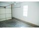 Unfinished garage with concrete floor, white walls, a small window, and roll-up door at 159 Valhalla Dr, Timberlake, NC 27583