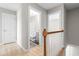 Upstairs hallway with light colored floors leading to a bathroom and bedroom with railing overlooking staircase at 1707 Stroll Cir, Fuquay Varina, NC 27526
