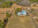 Aerial view of the beautiful home, featuring outbuildings, open land, and mature trees at 1834 Dewitt Smith Rd, Pittsboro, NC 27312