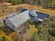 Wide aerial view of the white house with a metal roof, landscaping and surrounded by trees at 1834 Dewitt Smith Rd, Pittsboro, NC 27312