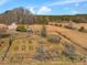 Aerial view of a charming property with garden area, outbuildings, surrounded by lush landscape at 1834 Dewitt Smith Rd, Pittsboro, NC 27312