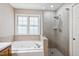 Bright bathroom featuring a soaking tub with window and a glass door shower at 2006 Chedington Dr, Apex, NC 27502