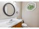 Half bathroom featuring a vanity sink, round mirror, toilet, and a decorative window at 2006 Chedington Dr, Apex, NC 27502