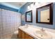 Blue bathroom featuring double sinks and a shower with decorative curtains at 2006 Chedington Dr, Apex, NC 27502