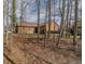 Brick home backyard surrounded by woods with mature trees and a well-maintained lawn at 2504 Churchill Dr, Burlington, NC 27215