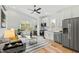 Open-concept living room and kitchen with a modern sofa, stainless steel appliances, and bright natural light at 2730 Milburnie Rd, Raleigh, NC 27610