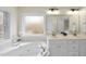 Well lit bathroom with double sink vanity and tub next to frosted window at 2905 Whitehart Ln, Raleigh, NC 27606