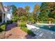 Beautiful backyard featuring a sparkling pool, brick patio, and lush landscaping, perfect for relaxation at 303 Laurel Hill Road, Chapel Hill, NC 27514
