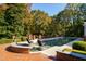 Lush backyard featuring a sparkling pool, brick patio, and mature trees, creating a private oasis at 303 Laurel Hill Road, Chapel Hill, NC 27514