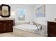 Bright bathroom featuring a soaking tub with granite surround, a large window and brown cabinets at 303 Laurel Hill Road, Chapel Hill, NC 27514