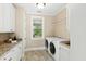 Bright laundry room with white cabinets, granite counters and a window with a backyard view at 303 Laurel Hill Road, Chapel Hill, NC 27514