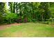 Grassy backyard has lush, mature trees and a partial fence at 3614 Kilgo Dr, Durham, NC 27705