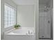 Corner tub and shower with glass door is surrounded by a frosted window for natural light at 3614 Kilgo Dr, Durham, NC 27705