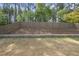 View of the backyard featuring a wooden fence and retaining wall with lush trees at 3621 Colby Chase Dr, Apex, NC 27539