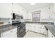 Kitchen features a gas range, stainless steel microwave, granite countertops, and white cabinetry at 3719 Hermine St, Durham, NC 27705