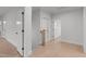 Hallway with light hardwood floors and white walls, leading to various rooms at 4508 Chandler Creek Pl, Apex, NC 27539