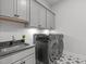Well-equipped laundry room with modern washer and dryer, storage cabinets, and a utility sink at 4508 Chandler Creek Pl, Apex, NC 27539