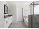 Bright bathroom featuring dual sinks, vanity, soaking tub and a tiled shower with glass door at 5112 Lizard Tail Ln, Raleigh, NC 27603