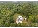 Aerial view of a home surrounded by trees, featuring a lush lawn, long driveway, and unique architecture at 5217 Tanglewild Dr, Raleigh, NC 27613
