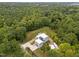 Aerial view of modern home surrounded by trees, a lush lawn, long driveway, and unique architecture at 5217 Tanglewild Dr, Raleigh, NC 27613