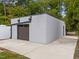 Modern garage on concrete pad, lush greenery, and a convenient side door, perfect for storage and parking at 5217 Tanglewild Dr, Raleigh, NC 27613