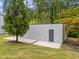 Modern outbuilding on a lush lawn, complemented by a variety of trees and convenient access to a concrete pad at 5217 Tanglewild Dr, Raleigh, NC 27613