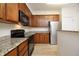 Well-equipped kitchen with stainless steel refrigerator, black appliances, and wood cabinetry at 528 Weather Ridge Ln, Cary, NC 27513