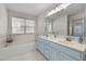 Bathroom featuring a tub, double sink vanity with large mirror and soft blue cabinets at 5401 Green Feather Ln, Raleigh, NC 27604