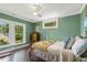 Sunlit bedroom featuring green walls, white trim, wood floors, and large windows at 613 S Fuquay Ave, Fuquay Varina, NC 27526