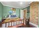 Bedroom featuring green walls, hardwood floors, white trim, and decorative brick accent wall at 613 S Fuquay Ave, Fuquay Varina, NC 27526