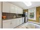 A charming kitchen featuring white cabinetry, a stainless steel refrigerator, and a dark tile backsplash at 613 S Fuquay Ave, Fuquay Varina, NC 27526