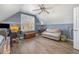 An attic bedroom features wood flooring, a window, a ceiling fan and a comfy couch at 761 Raymond Dr, Clayton, NC 27527