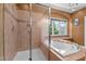 Bathroom featuring both a glass shower and soaking tub next to a large window with a wooded view at 7709 Moondance Ct, Wake Forest, NC 27587