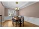 Formal dining area with decorative chandelier, beautiful hardwood floors, and large window providing natural light at 7709 Moondance Ct, Wake Forest, NC 27587