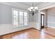 Elegant dining room featuring a chandelier, chair rail, hardwood floors and large windows at 9041 Chelsea Dr, Raleigh, NC 27603