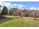 Expansive front yard with lush greenery, showcasing a beautiful brick home with mature trees and manicured landscaping at 9041 Chelsea Dr, Raleigh, NC 27603