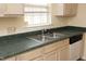 Close-up of a stainless steel sink with green countertops and light wood cabinets at 104 Hickory Glen Ln, Durham, NC 27703