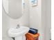 A charming bathroom with a pedestal sink, round mirror, and a small wooden table with a basket at 105 Palladium Ct, Elon, NC 27244