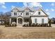 Elegant two-story home featuring stone accents, white siding, and a welcoming front porch with rocking chairs at 1225 Perry Bluff Dr, Wake Forest, NC 27587