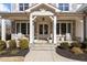Charming front porch with double doors adorned with wreaths, white rocking chairs, and stone accents at 1225 Perry Bluff Dr, Wake Forest, NC 27587
