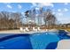 Pool with bright blue water surrounded by lounge chairs and mature trees at 1225 Perry Bluff Dr, Wake Forest, NC 27587