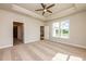 Spacious main bedroom featuring a tray ceiling, ceiling fan, large window, and neutral carpeting at 133 Oban Dr, Homesite 151, Sanford, NC 27330